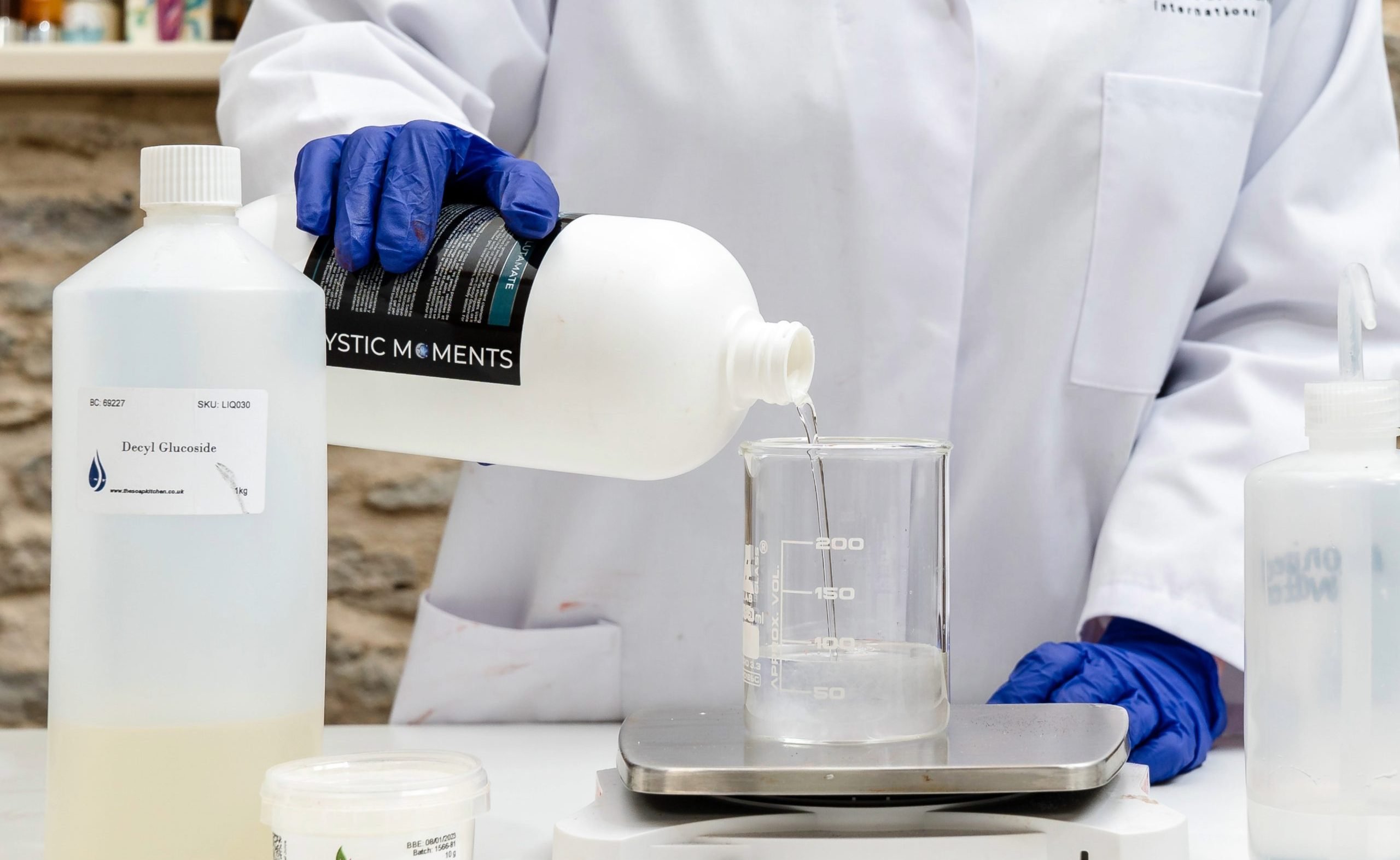 Weighing surfactants Scientist pouring liquid into a beaker on scale.